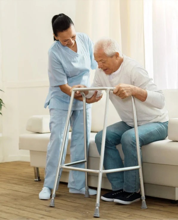 A nurse steadying a client as they move with a walking frame